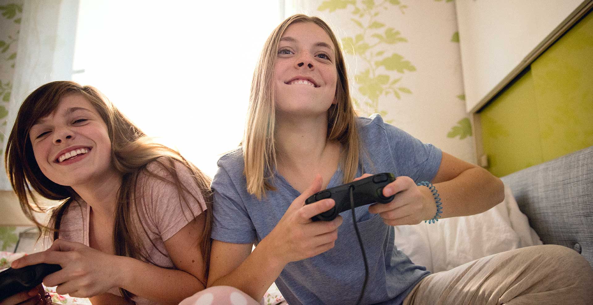 Zwei Mädchen spielen Computerspiel und lachen.
