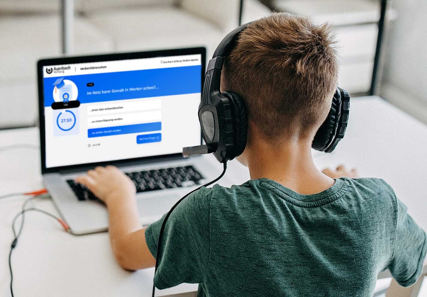 Ein Junge mit großen Kopfhörern schaut auf einen Computerbildschirm mit der geöffneten Medienführerschein-Seite.