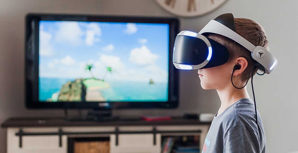 Ein Junge soielt mit einer VR-Brille ein Computerspiel