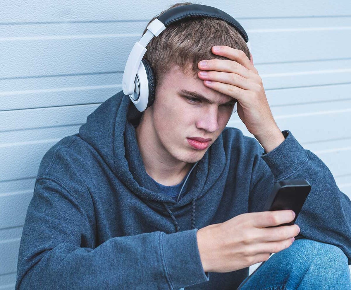 Teenager schaut traurig in sein Handy