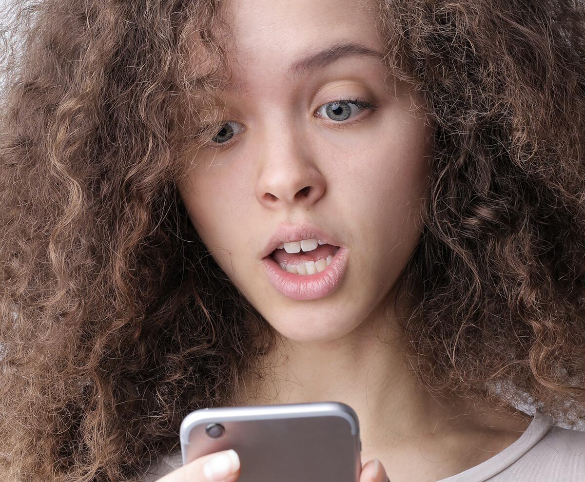 Ein junges Mädchen schaut erschrocken auf ihr Handy