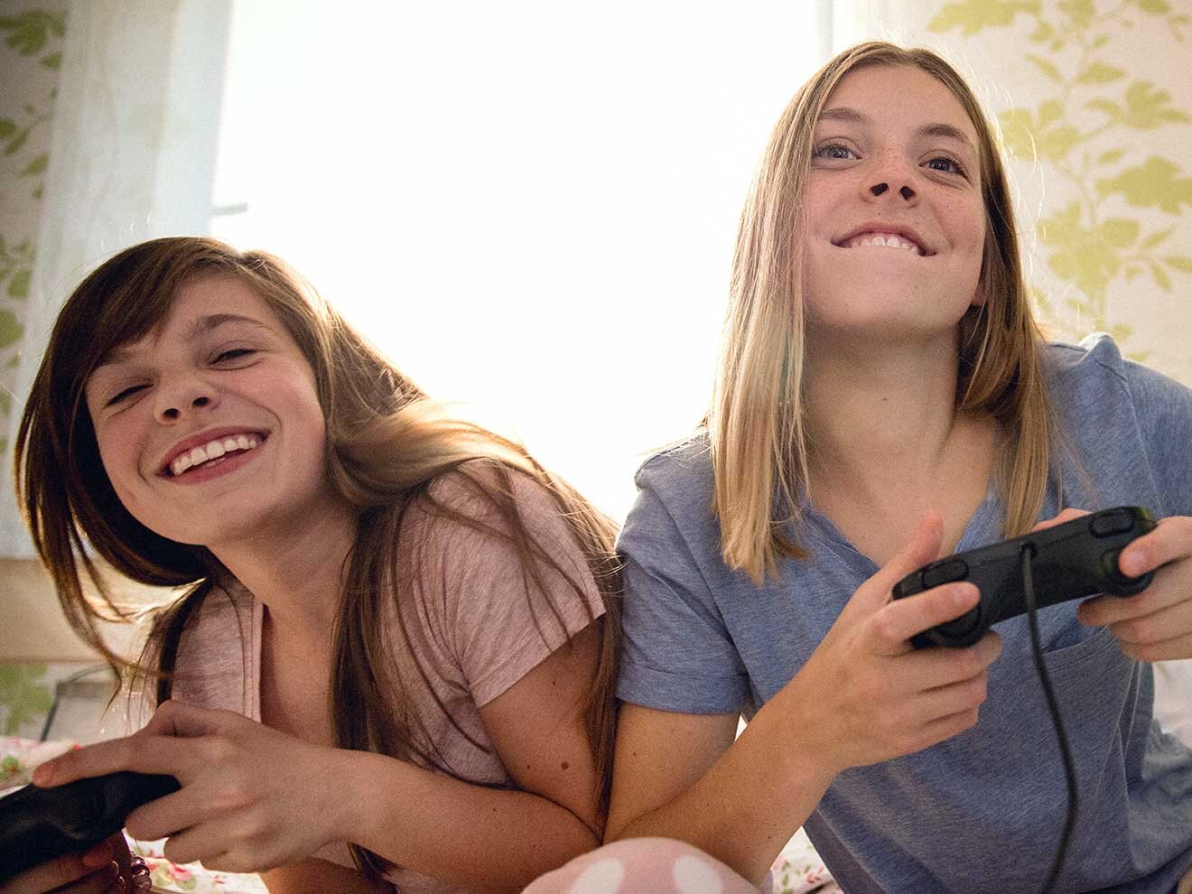 Zwei Mädchen spielen Computerspiel und lachen.