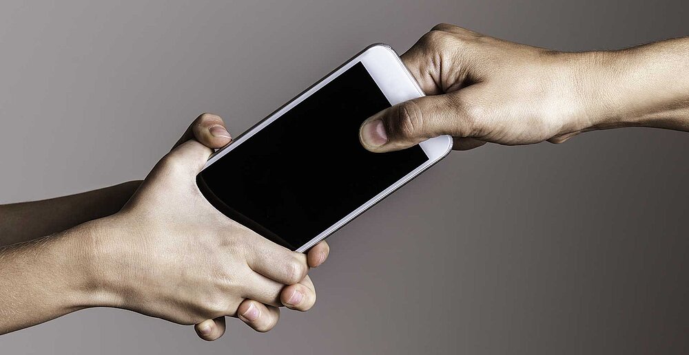 Zwei Hände zerren an einem Handy