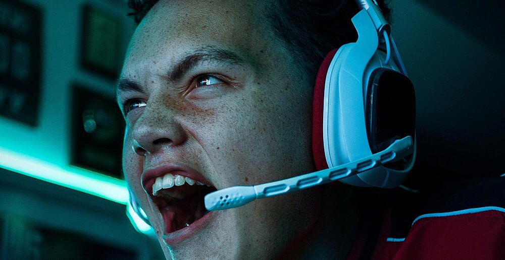 Ein Teenager mit Headset schreit, während er ein Computerspiel spielt