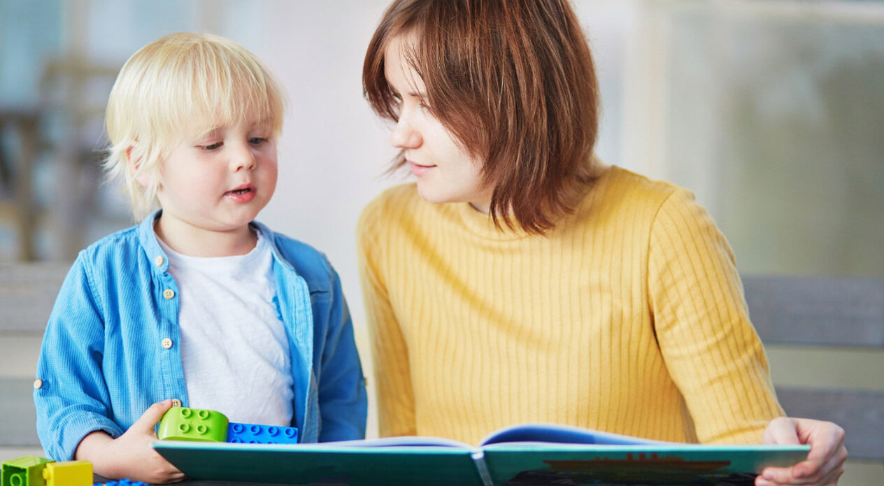 Eine junge Mutter liest ihrem kleinen Sohn aus einem Buch vor.